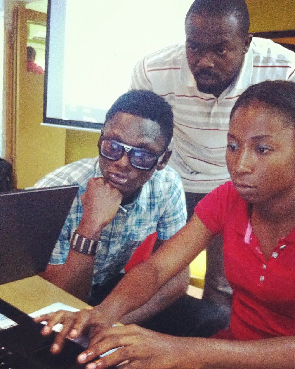 Three young Nigerians working together at a laptop
