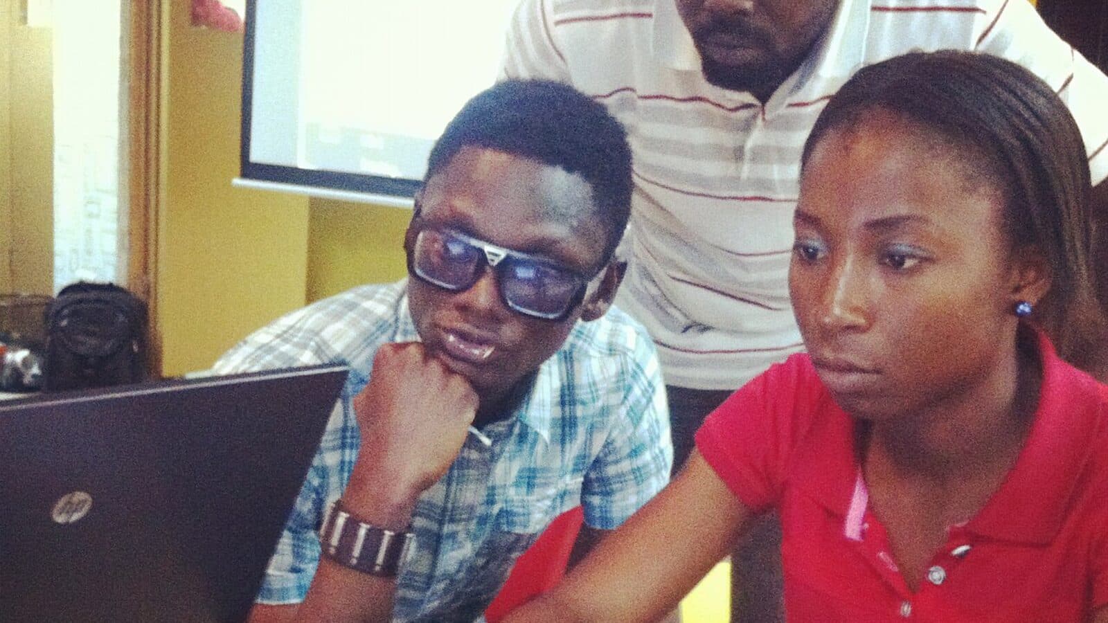 Three young Nigerians working together at a laptop in Lagos