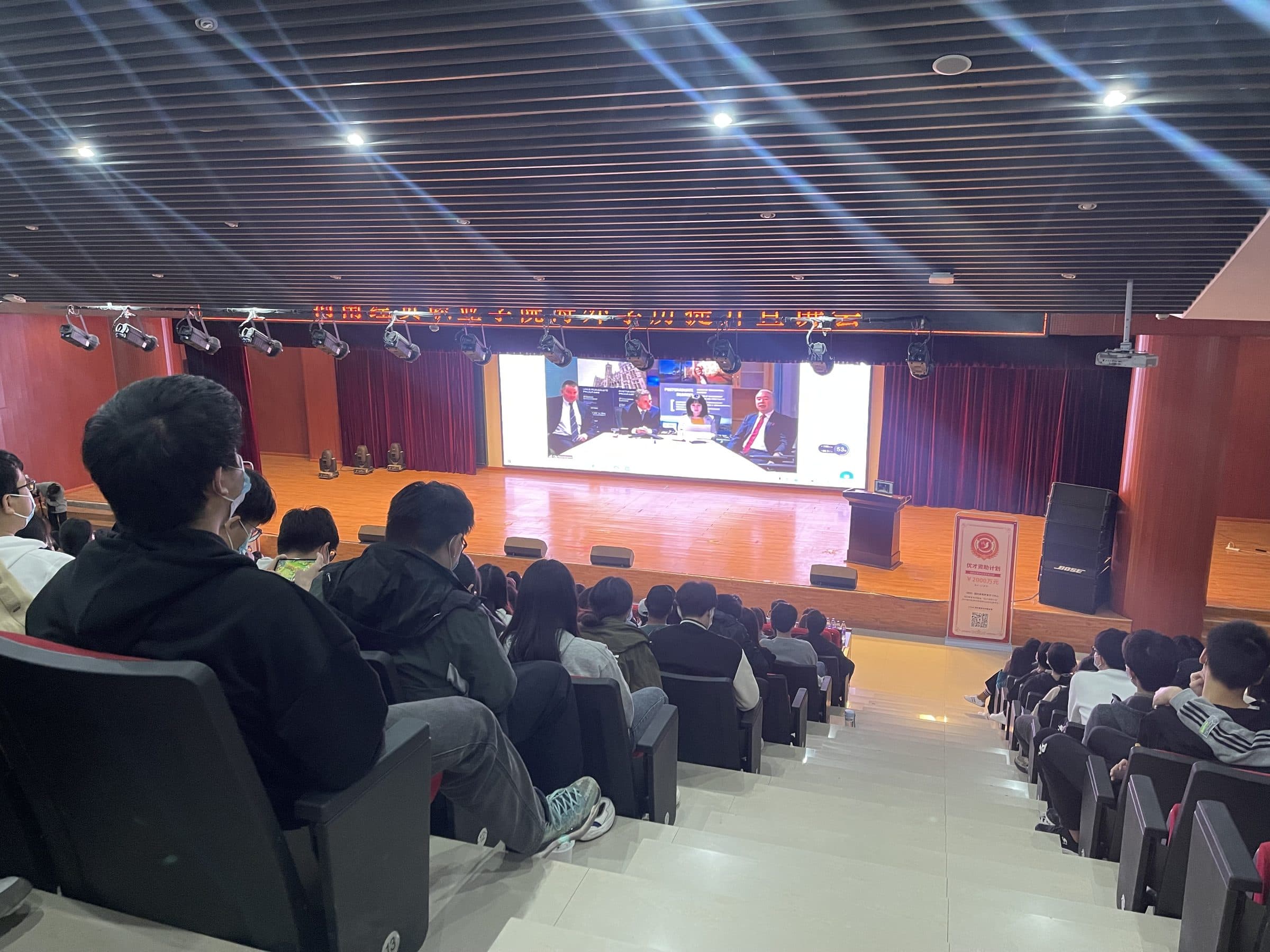 A live video link with international partners shown on the auditorium screen